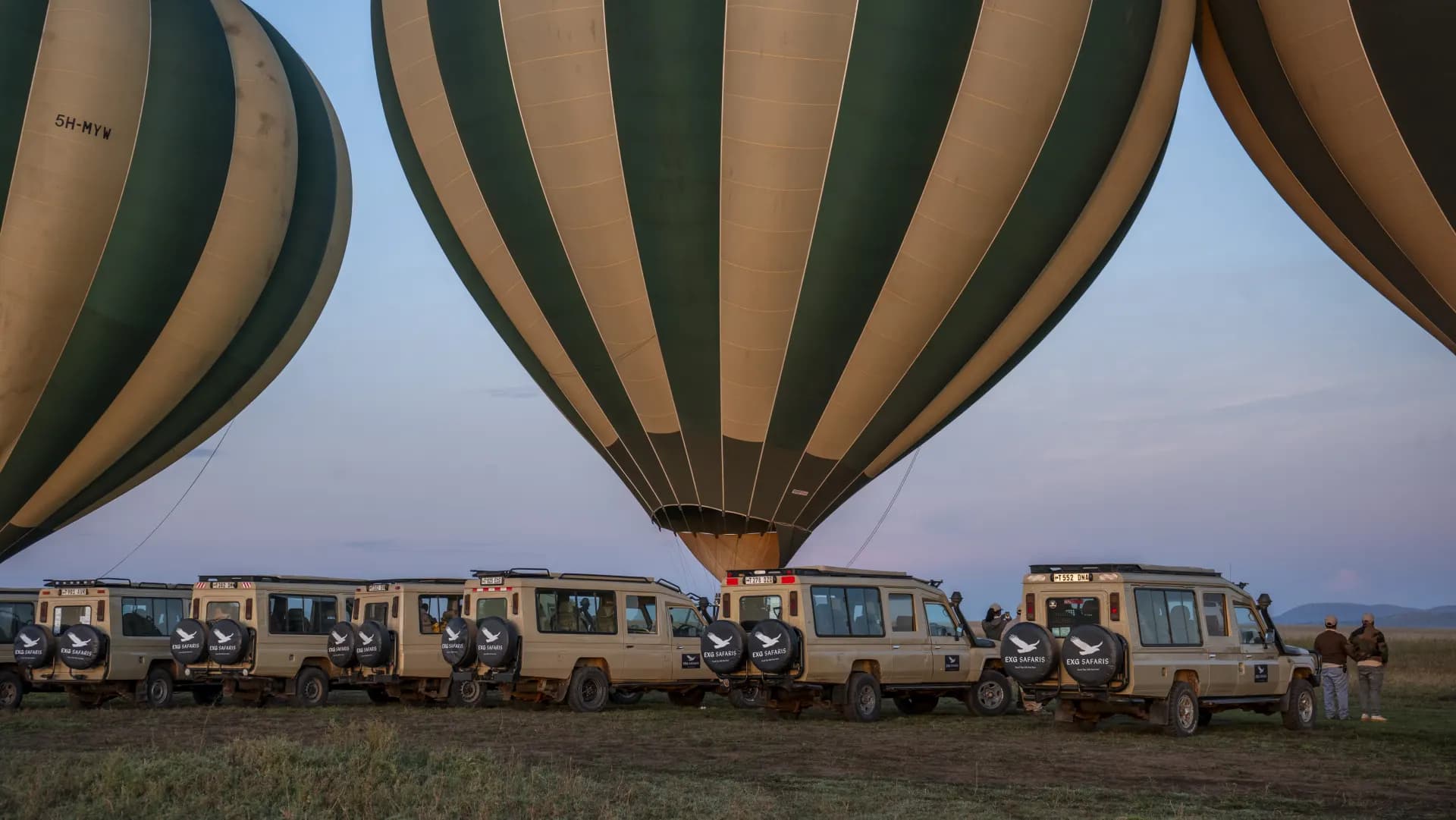 Two hot air balloons in flight at dawn over the Serengeti, guests visible in the basket