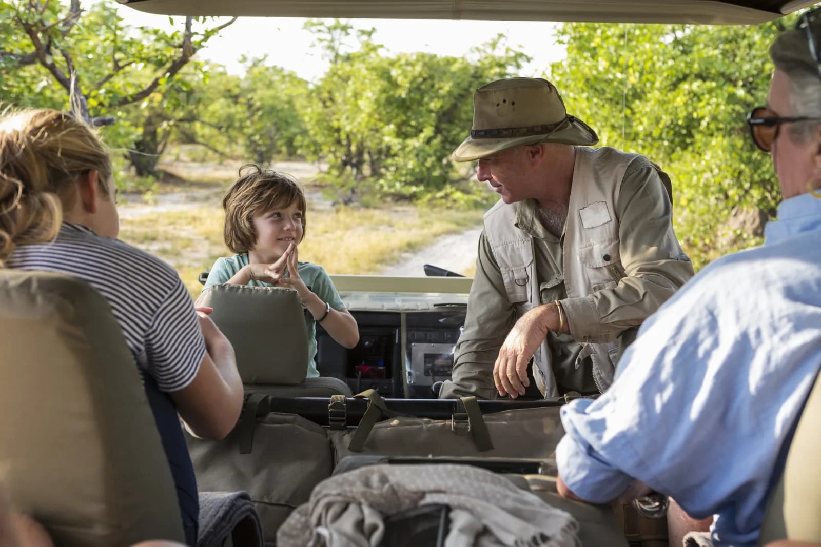 A driver-guide talking with a child in the safari vehicle