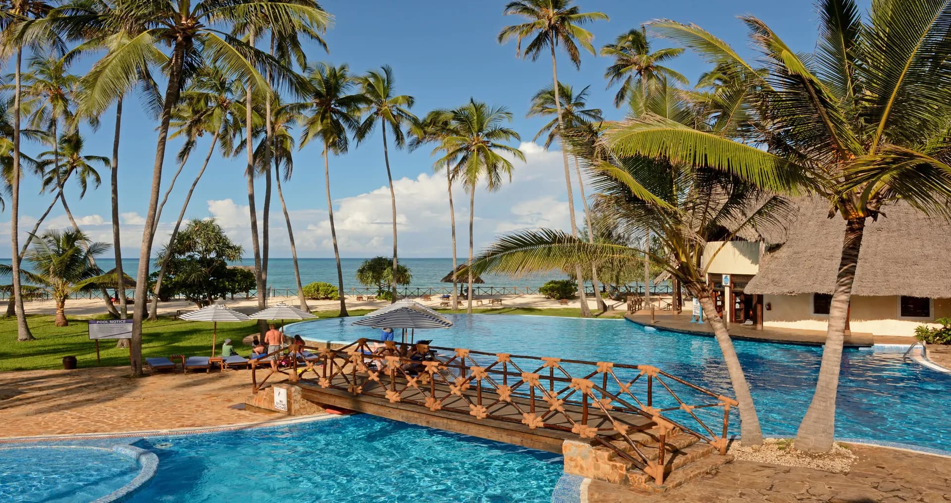 Poolside loungers and palm trees at a Zanzibar beach resort, with the Indian Ocean in the background